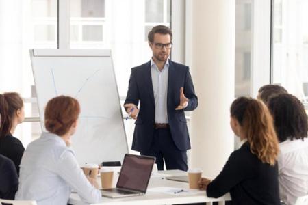man with white board leading meeting with five people around the table