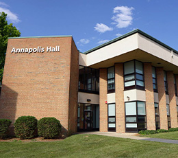 The exterior of Annapolis Hall, a brick academic building on the Frederick Community College campus, on a sunny day with a blue sky.