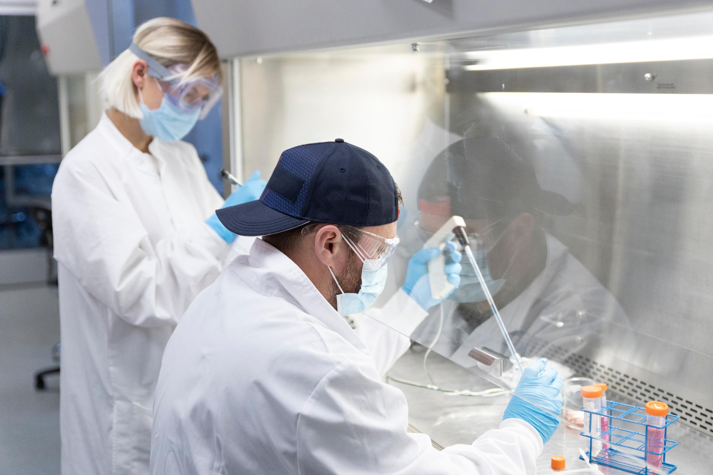2 scientists in white lab coats performing experiments.